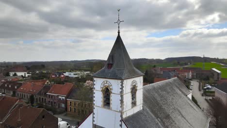 Rotación-De-Drones-Aéreos-Alrededor-Del-Reloj-De-La-Iglesia-Con-Colinas-Belgas-En-El-Fondo