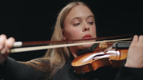 pretty young female fiddler is playing violin or viola in philharmonic hall portrait