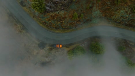 Top-shot-of-tourist-car-stopped-on-a-curvy-road-of-Shogran-Valley-in-Pakistan-during-a-foggy-day