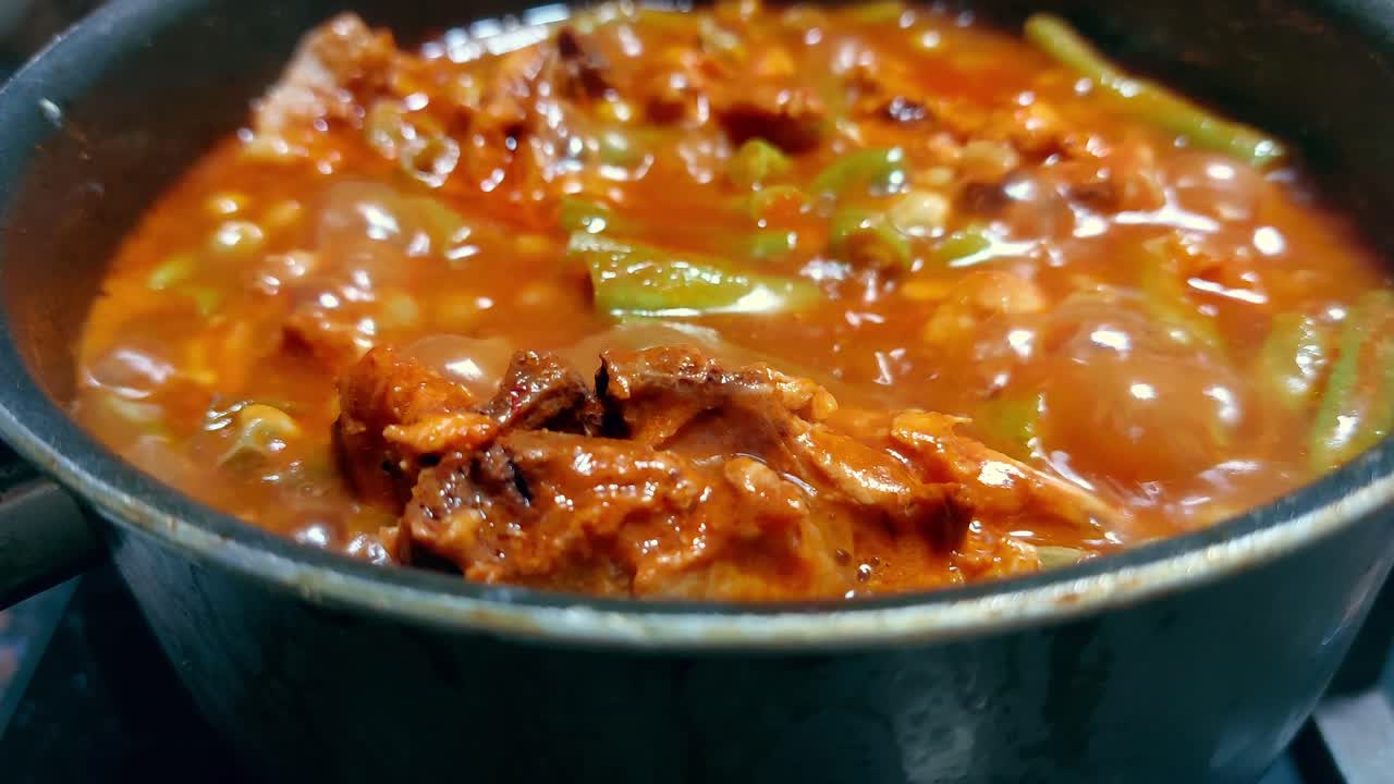Close up to a pot of simmering pork afritada which is a local traditional Filipino tomato base stew cooked at home