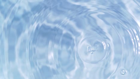 top view slow motion of drop falling into the water surface and diverging circles on white background