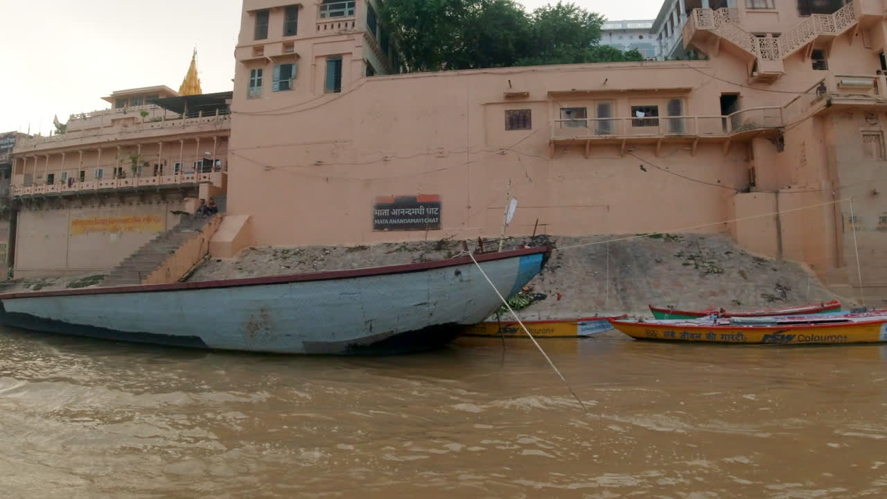 cinematográfico en cámara lenta varanasi india río ganges capitán de crucero barcos del canal estado del norte reuniéndose antigua ciudad santa provincia de ghat pradesh paisaje gris nublado por la tarde marrón fangoso a la izquierda