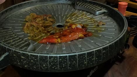 placing meat on korean barbecue in restaurant to grill, close up