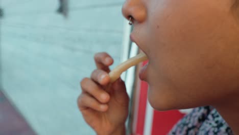 Detailed-shot-of-an-unrecognizable-young-woman-is-captured-pouring-ketchup-on-a-potato-and-subsequently-enjoying-her-snack,-showcasing-a-moment-of-simple-culinary-pleasure