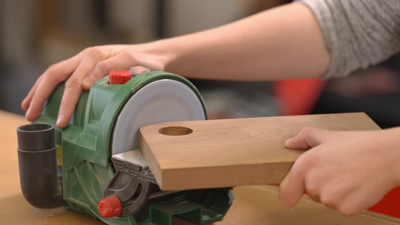 Video al rallentatore della levigatura di un'asse di legno con una levigatrice a disco in un'officina. Processo di finitura del legno, preparazione di superfici lisce, artigianato e controllo preciso degli attrezzi.