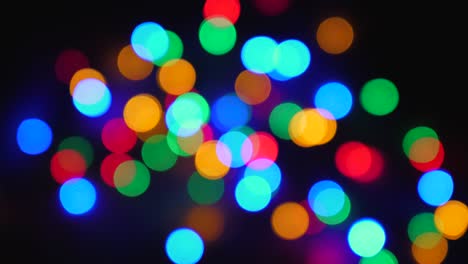 blurred twinkling multi-colored holiday lights on black background