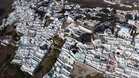 oia village cliffside houses and hotels in santorini, greece, cinematic aerial view