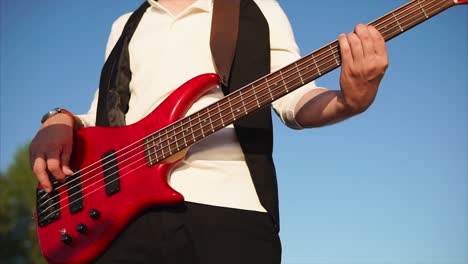 man playing red bass guitar outdoors