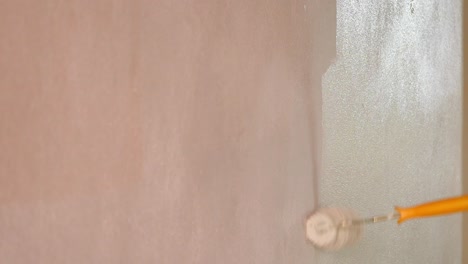 applying paint to a wall with a roller during a home renovation