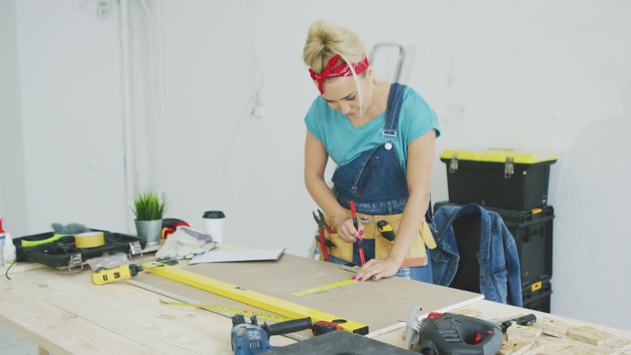 Woman drawing line on plywood in workshop 