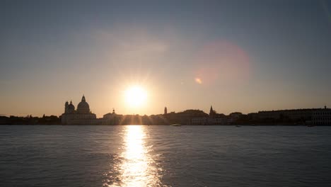 Sunset-on-the-lagoon-with-ferries-passing-in-front-of-Piazza-San-Marco,-Venice