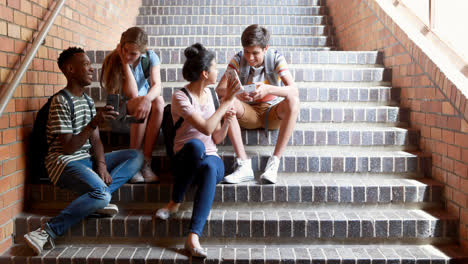 classmates sitting on staircase and using mobile phone
