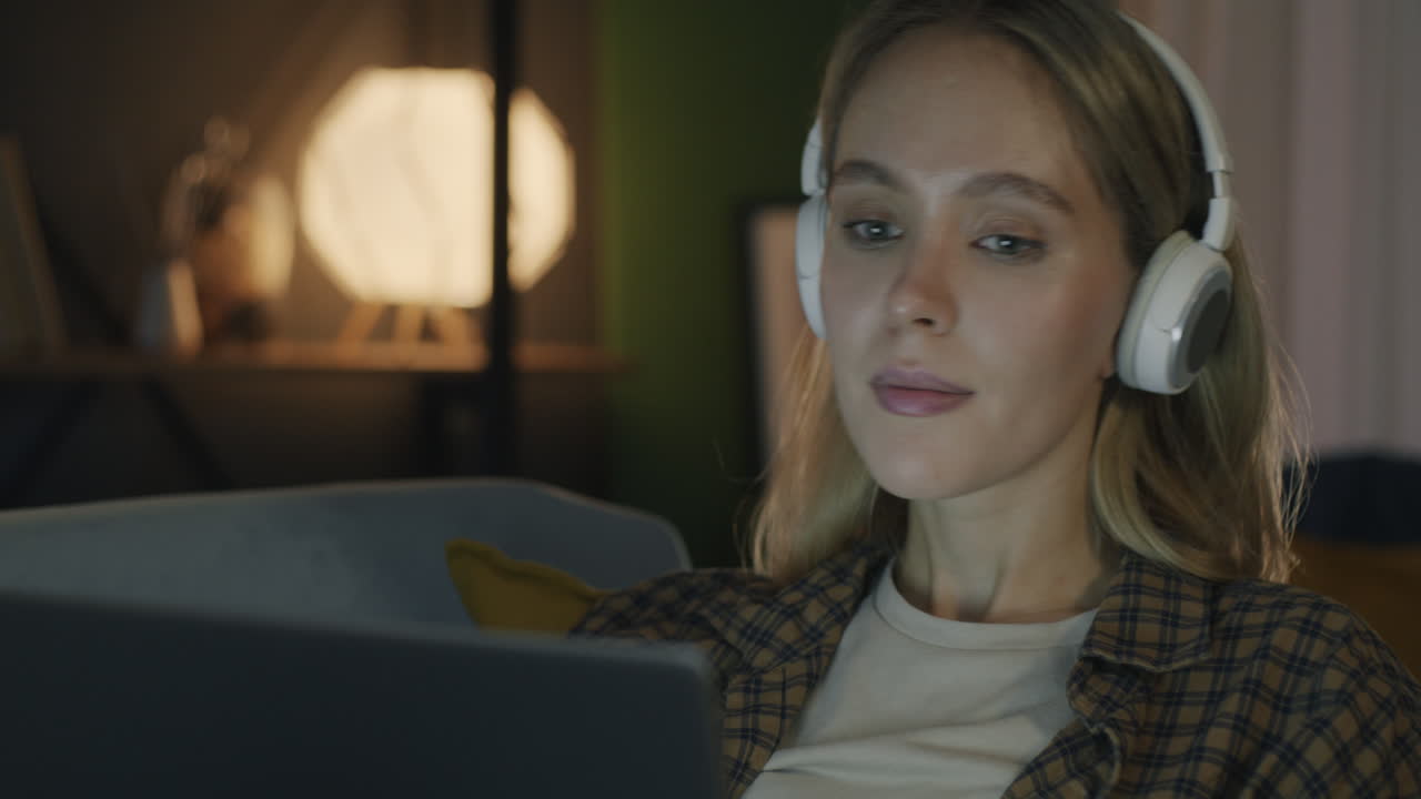Woman Relaxing on Sofa with Headphones and Laptop