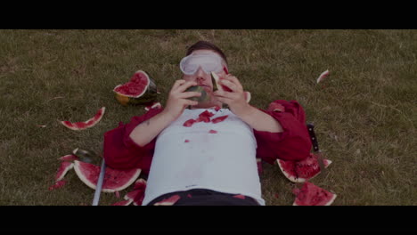 man eating watermelon in the grass