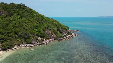 drone flight over beach with wooden path walking around island