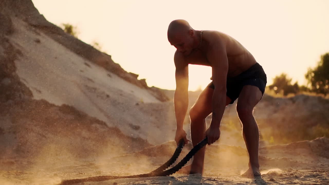 Workout with a rope and a sports man an athlete sandy.