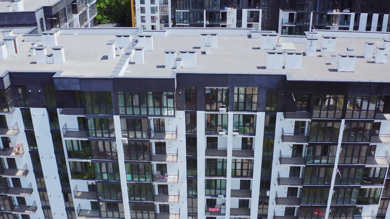 New house for city residents. Contemporary apartment building with large windows and beautiful walls of the facade. City landscape reflects in the windows of a high-raised building. Aerial view.