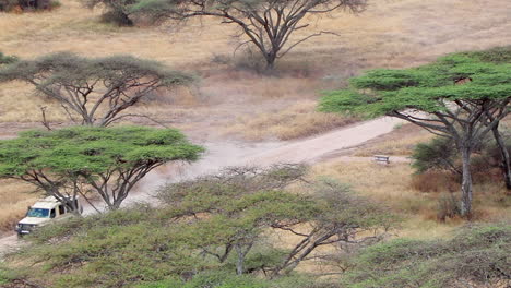 A-Safari-Jeep-Drives-Down-a-Dirt-Road-in-the-Serengeti,-Static,-Telephoto-Shot