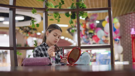 young lady sitting at table in front of mirror, smiling as she selects preferred makeup item, surrounded by beauty products and a stylish ambiance, she enjoys personal grooming and self-care moment