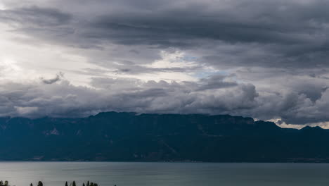 Clouds-And-Mist-Flying-Above-Calm-Lake-Leman-In-Switzerland-With-Majestic-French-Alps-In-Background