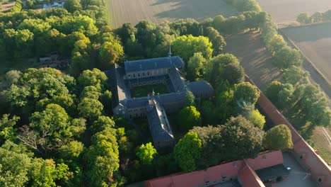 beautiful scenery of a monastery middle of the nature surrounded by green trees in the early morning next to a farm