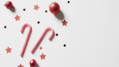 video of candy canes, baubles and stars, christmas decorations with copy space on white background