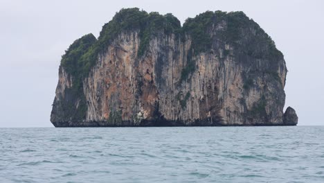 un barco se acerca a la pintoresca isla de roca en krabi, tailandia