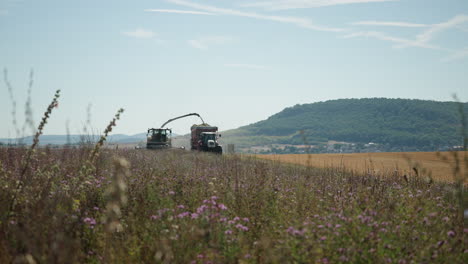 vista de la cosechadora y el tractor conduciendo lentamente por el campo en rhön grabfeld, alemania