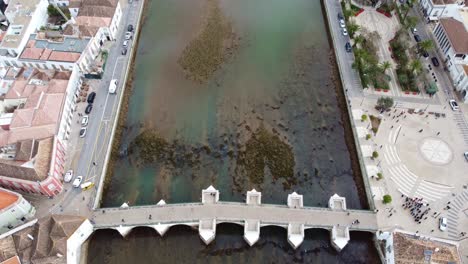 Drohnen-Enthüllungsaufnahme-In-Tavira,-Algarve,-Portugal,-Schwenk-Von-Der-Brücke-Ponte-Romana-Entlang-Des-Galao-Flusses-Zum-Atlantischen-Ozean,-Auch-Mit-Der-Salzlagune-Kurz-Vor-Dem-Meer