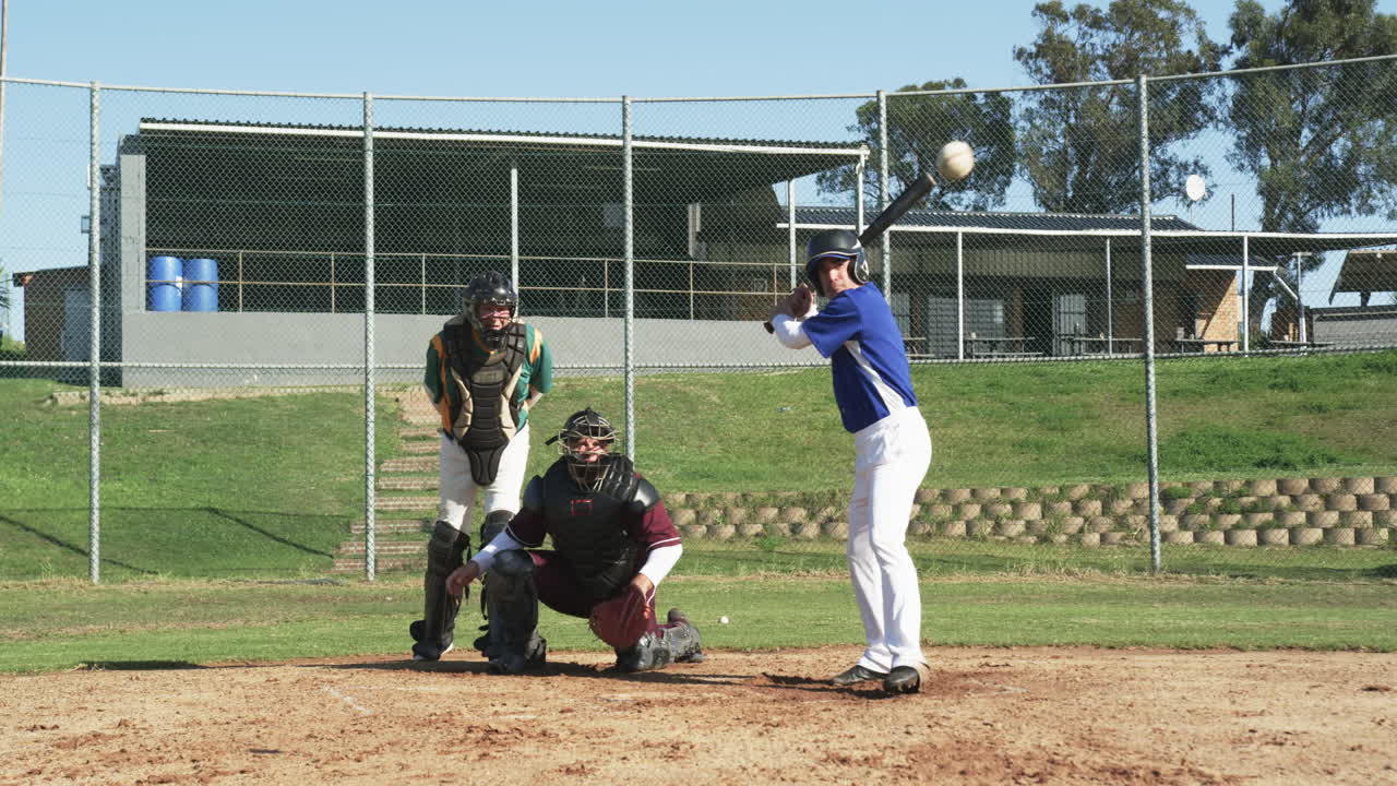 Giocatori di baseball e un arbitro che giocano a baseball, colpendo la palla e correndo sul campo, al rallentatore.