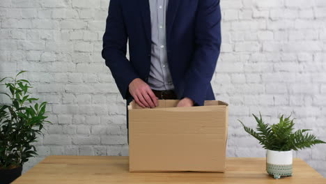 a man fired from work is packing a box on his desk and leaving his job as unemployed