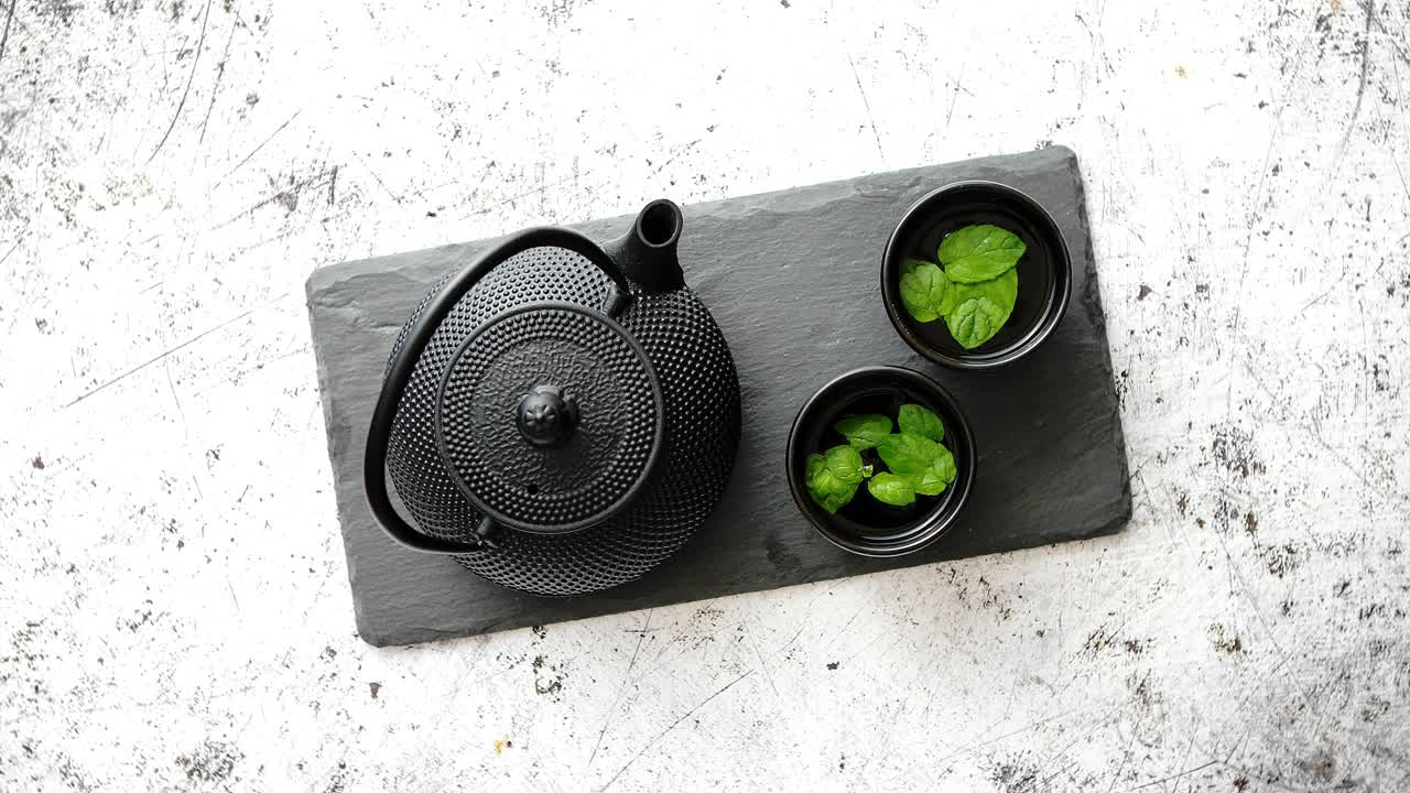 tetera de metal oriental tradicional y tazas de hierro