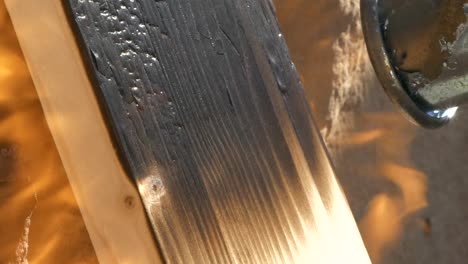 top of propane blowtorch applying strong fire on wood plank, macro close up slow motion