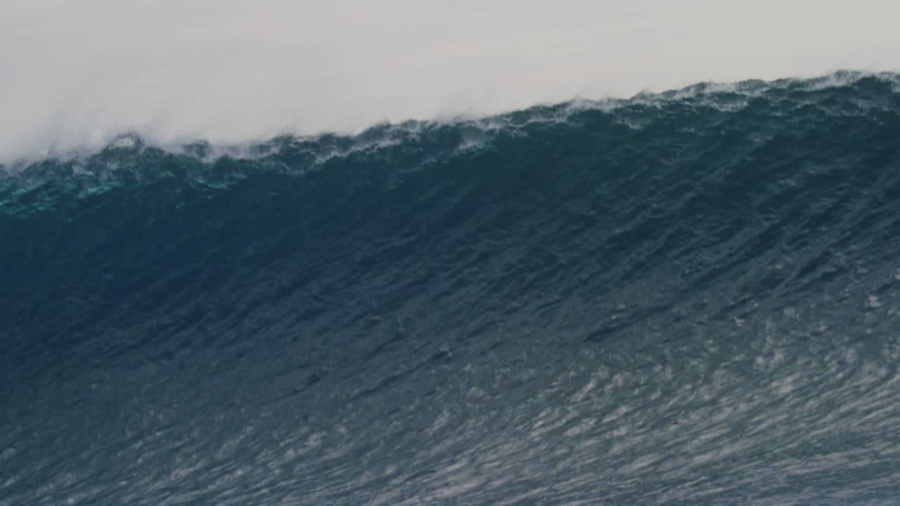 agua texturizada de una ola pesada que se eleva al barril y el labio que se arroja hacia abajo a medida que la niebla se eleva de la parte superior de la ola en cámara lenta