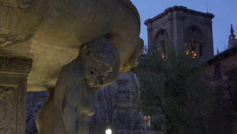 gárgola de una antigua fuente con un campanario de la catedral al fondo en granada