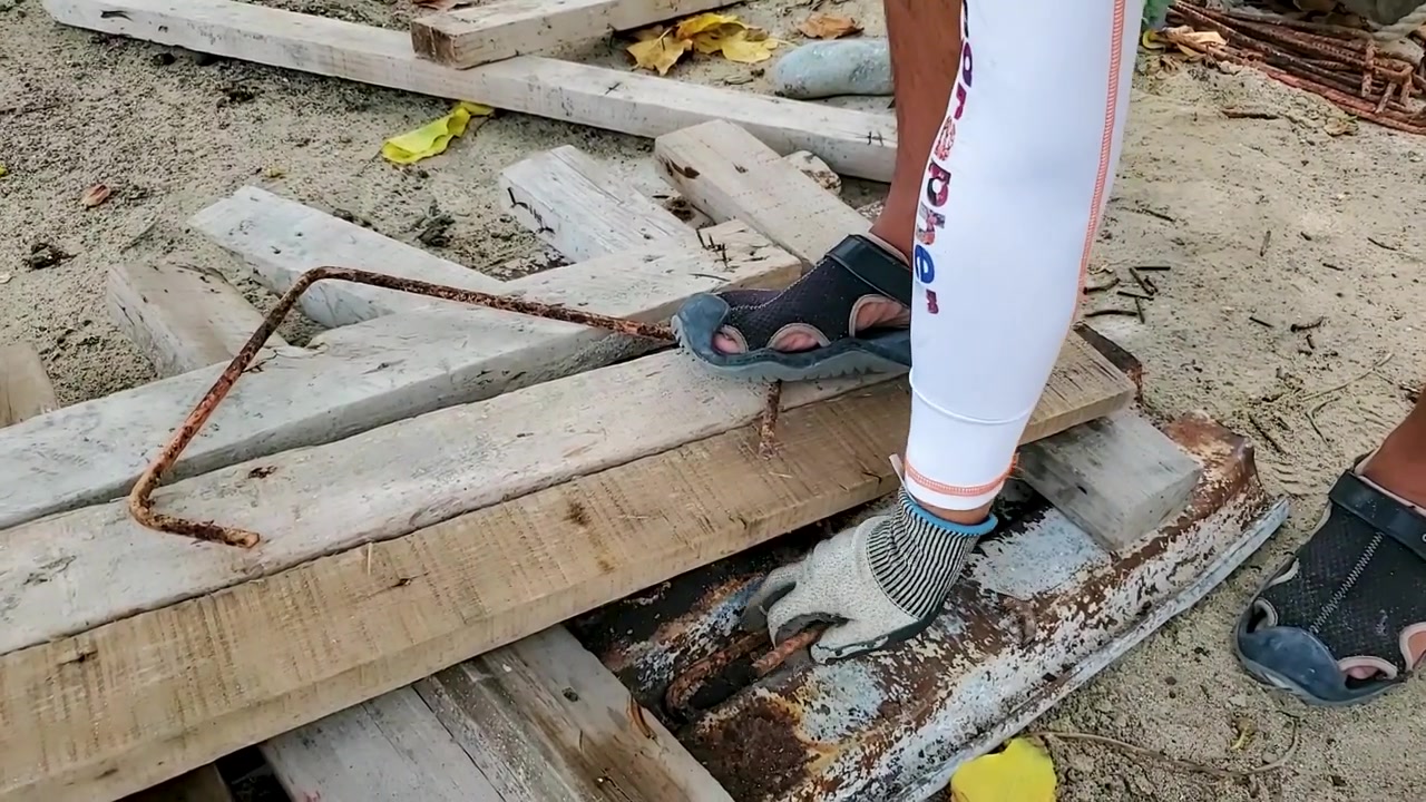 Primer plano de las manos de un hombre cortando metal con una amoladora eléctrica sobre madera, trabajador en riesgo con chispas rojas volando