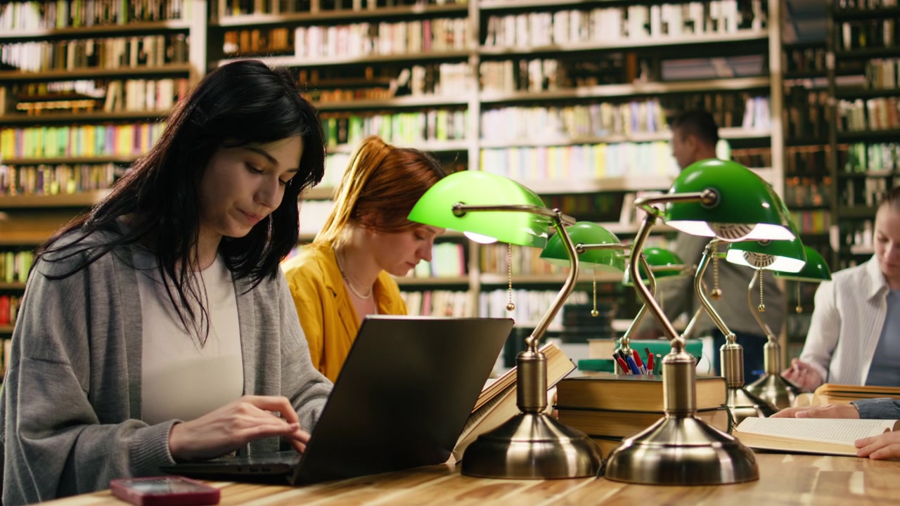 Studente che ignora il lavoro al laptop e gli appunti dopo una notifica dal telefono.