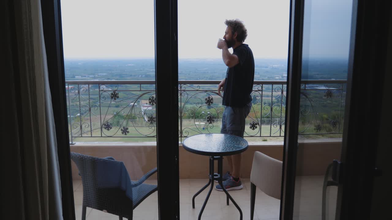 hombre tomando café en un balcón con una vista impresionante