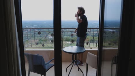 man drinking coffee on a balcony with a stunning view