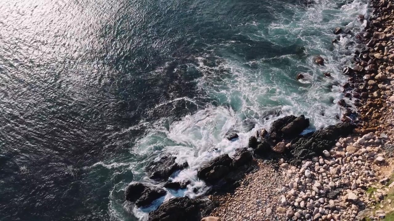 Onde oceaniche riprese dall'alto che si infrangono sulle rocce, primo piano medio.