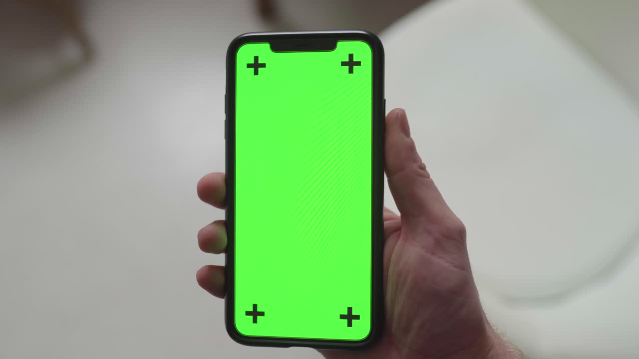 balanceando un teléfono inteligente frente a la cámara con pantalla verde y marcadores de seguimiento, estática