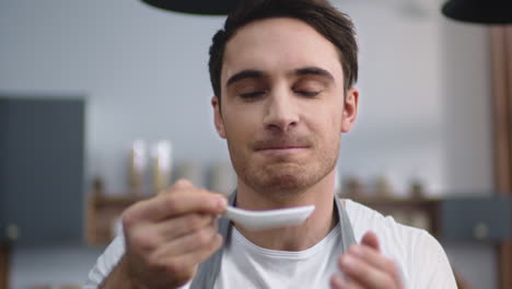 portrait of man cook tasting fresh soup at home kitchen. male chef cooking meal