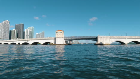 Blick-Von-Einem-Kleinen-Boot-Aus,-Als-Es-Sich-Einer-Brücke-In-Miami,-Florida,-Mit-Blauem-Himmel-Und-Blauem-Wasser-Näherte