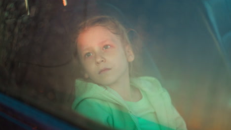 upset child sits in car on rainy day frustrated little girl looks at falling rain out of auto window