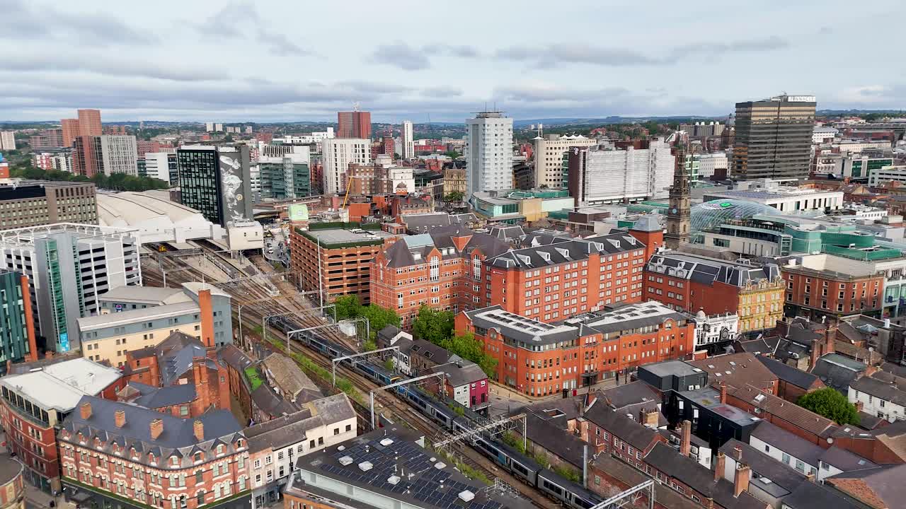 High-resolution aerial footage glides over central Leeds, highlighting Victorian architecture, modern buildings, and urban streets under soft daylight with steady camera movement