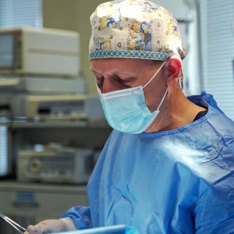 male surgeon in funny cap chooses tools during operation. doctor performing surgery. medical care concept