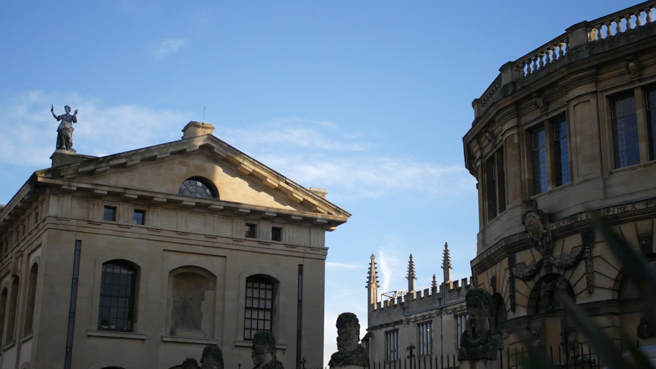 Edificio dell'Università di Oxford con frontone classico e statua sul tetto, ripreso in un'ampia veduta sotto un cielo blu che evidenzia l'architettura accademica storica e la simmetria