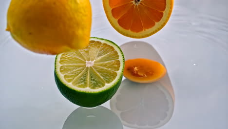 citrus fruits splashing on water