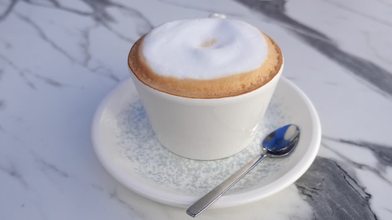 Cappuccino in a white cup on a marble table