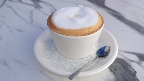 cappuccino in a white cup on a marble table